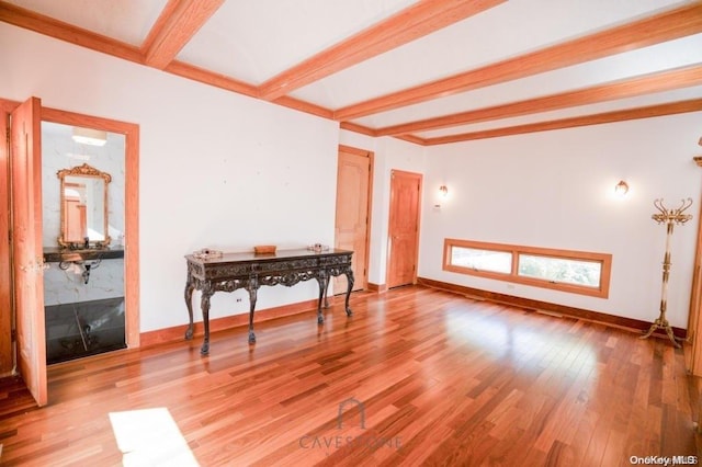 unfurnished room with beam ceiling and light hardwood / wood-style flooring