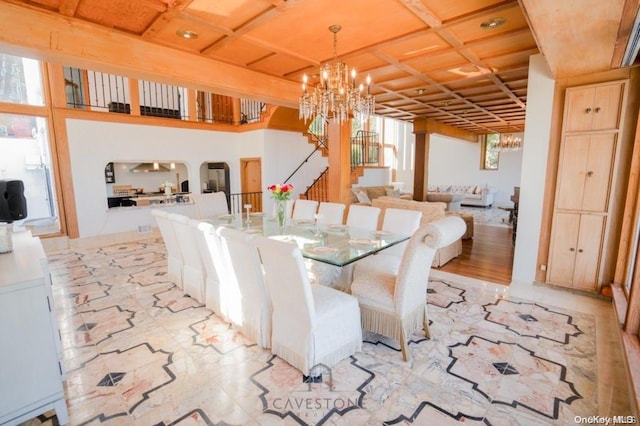 dining room featuring light hardwood / wood-style flooring, a healthy amount of sunlight, coffered ceiling, and a notable chandelier