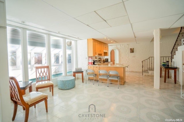 kitchen with a kitchen breakfast bar, a paneled ceiling, light brown cabinetry, and kitchen peninsula