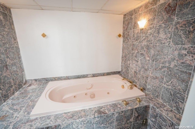 bathroom featuring a paneled ceiling and tiled tub