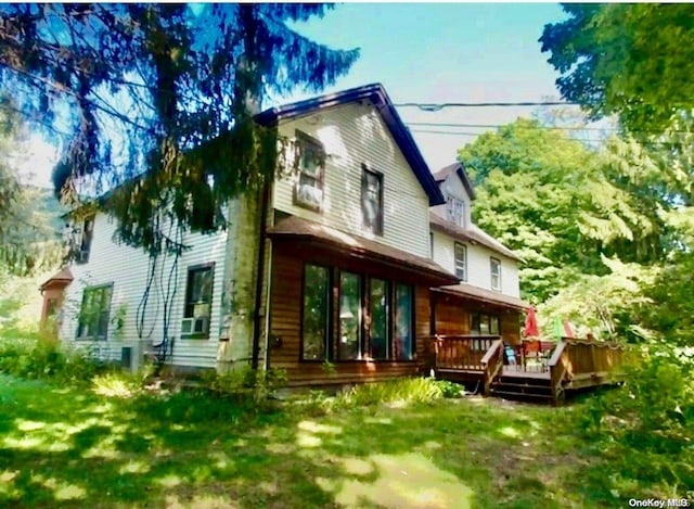 back of property featuring a lawn and a wooden deck