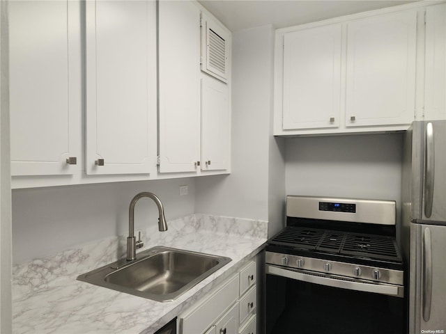 kitchen with appliances with stainless steel finishes, white cabinetry, and sink