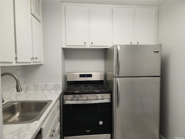 kitchen with white cabinetry, sink, stainless steel appliances, and light stone counters