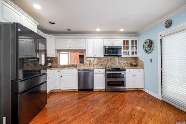 kitchen featuring appliances with stainless steel finishes, white cabinetry, crown molding, and hardwood / wood-style floors