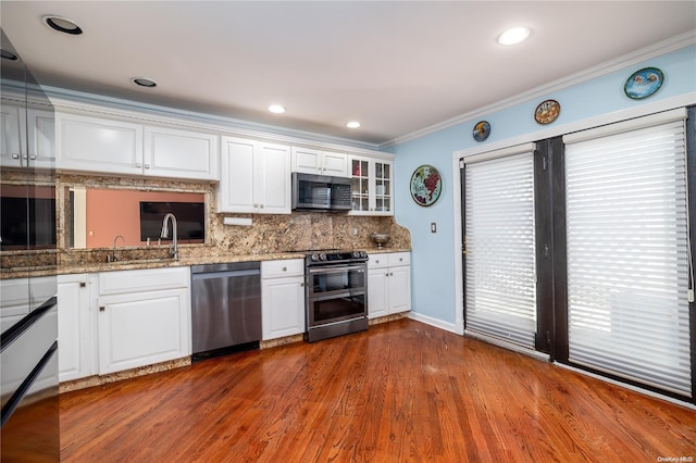 kitchen featuring white cabinets, crown molding, light stone countertops, dark hardwood / wood-style flooring, and stainless steel appliances