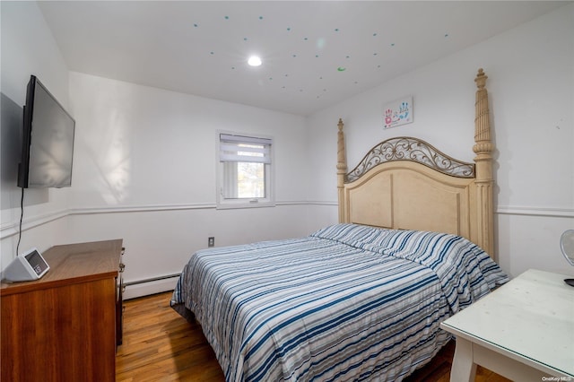 bedroom with wood-type flooring and a baseboard heating unit