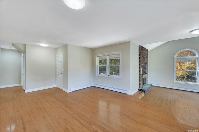 spare room featuring a fireplace, a baseboard radiator, lofted ceiling, and light wood-type flooring