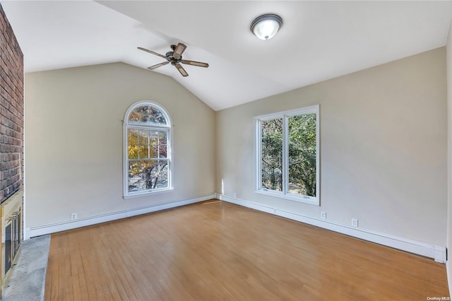 empty room with vaulted ceiling, light hardwood / wood-style flooring, baseboard heating, and ceiling fan