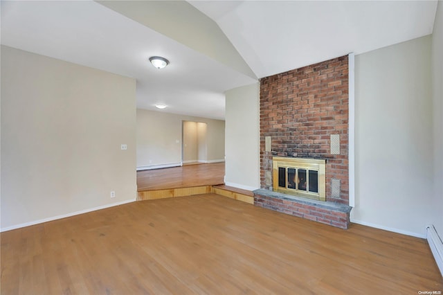 unfurnished living room featuring hardwood / wood-style flooring, baseboard heating, and a brick fireplace