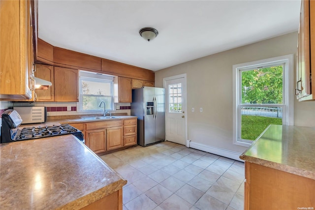 kitchen featuring backsplash, stainless steel appliances, sink, a baseboard radiator, and range hood