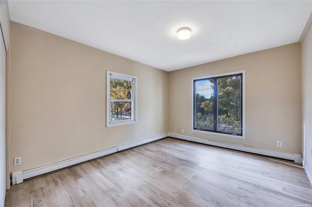 empty room with light wood-type flooring, plenty of natural light, and a baseboard heating unit