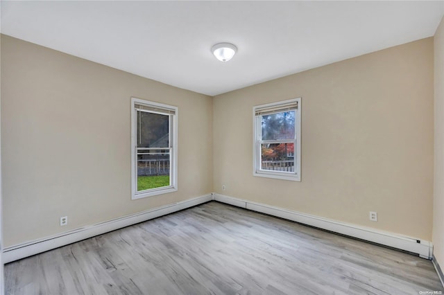 empty room featuring baseboard heating and light hardwood / wood-style flooring