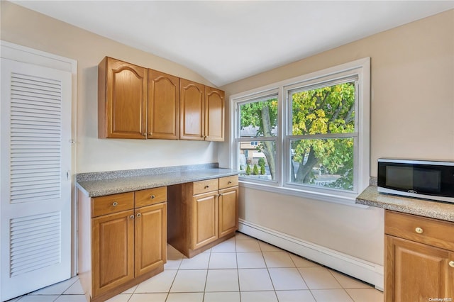 kitchen with a baseboard radiator, vaulted ceiling, and light tile patterned flooring