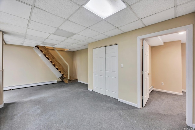 basement with carpet flooring, a drop ceiling, and a baseboard radiator