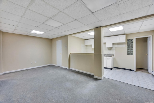 basement with a paneled ceiling and light tile patterned flooring