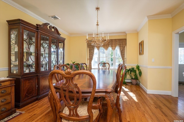 dining area with an inviting chandelier, light hardwood / wood-style flooring, and crown molding