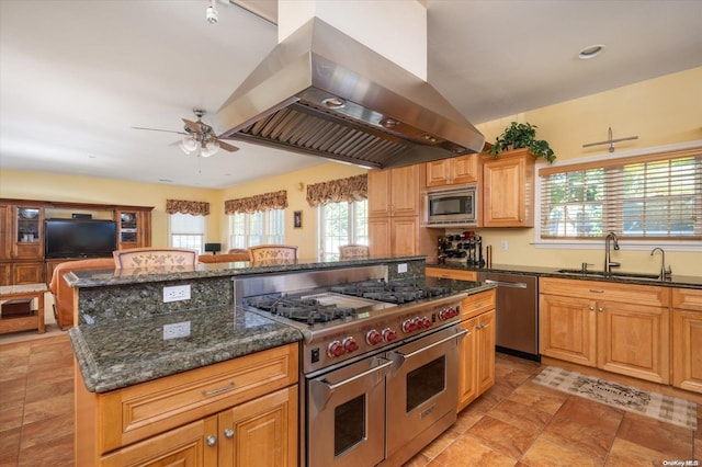 kitchen featuring sink, a healthy amount of sunlight, island exhaust hood, a kitchen island, and appliances with stainless steel finishes