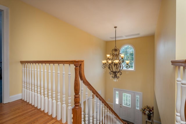 stairway with hardwood / wood-style floors and a chandelier