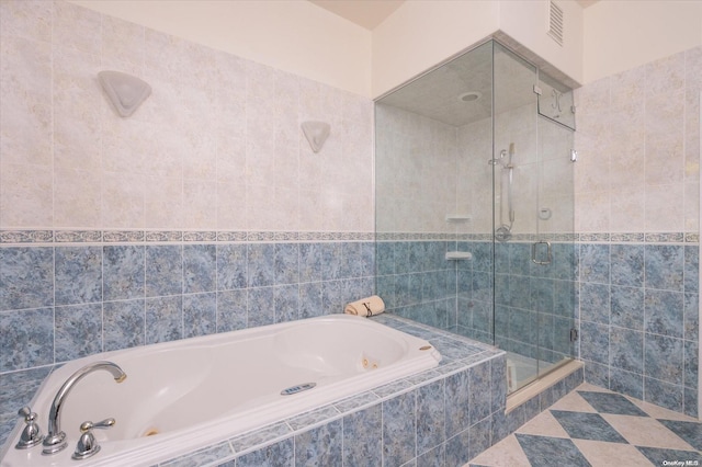 bathroom with tile walls and independent shower and bath