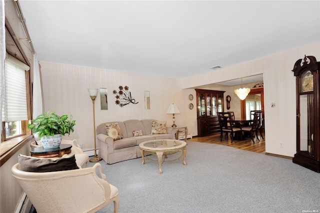 living room with carpet floors, a chandelier, and a baseboard heating unit