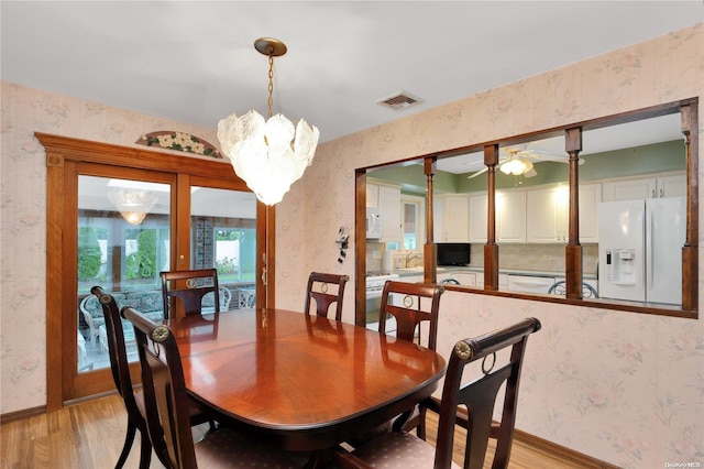 dining room with ceiling fan with notable chandelier and light wood-type flooring