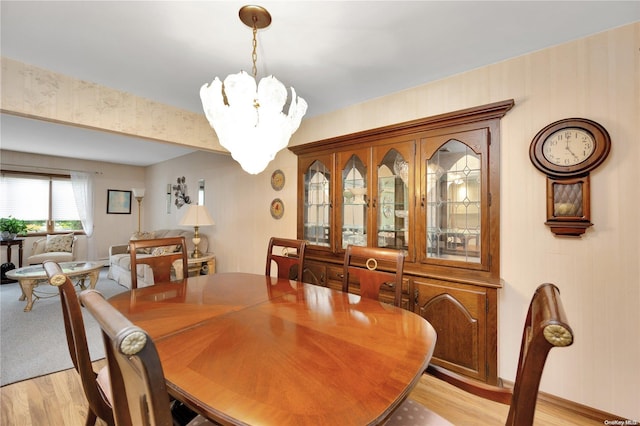 dining room with light wood-type flooring and an inviting chandelier