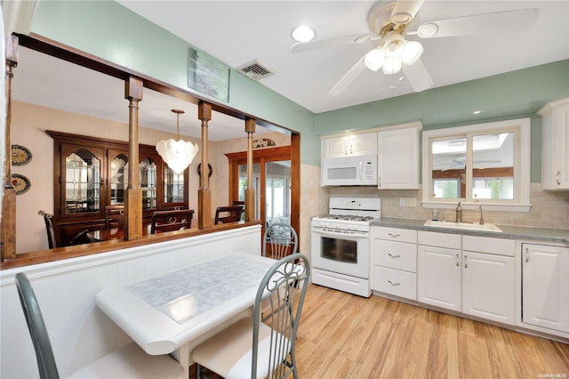 kitchen featuring white appliances, decorative light fixtures, white cabinetry, and sink