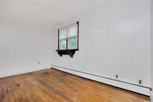 empty room with wood-type flooring, baseboard heating, and ornamental molding