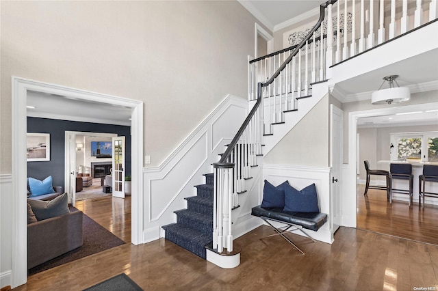 stairs featuring hardwood / wood-style floors, a towering ceiling, and crown molding