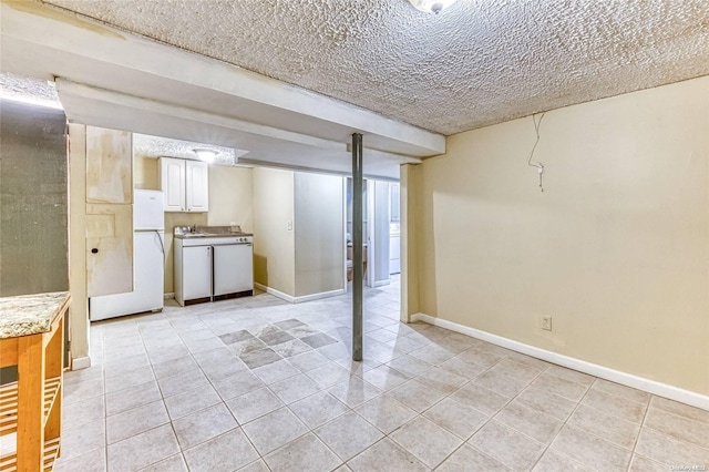 basement with light tile patterned floors, white fridge, and a textured ceiling