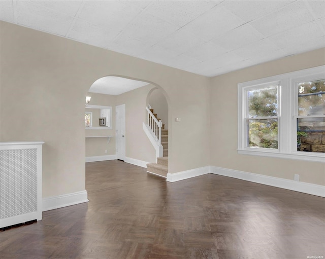 spare room featuring radiator and dark parquet floors