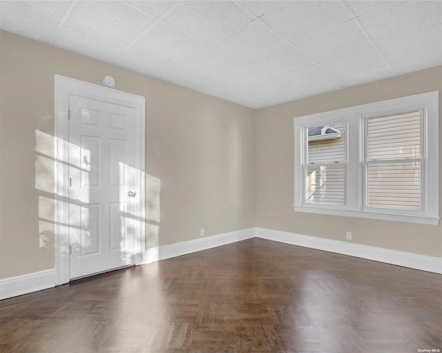 spare room with dark parquet flooring and a paneled ceiling