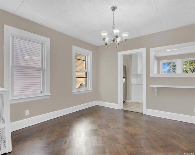 unfurnished dining area with a notable chandelier and dark parquet floors