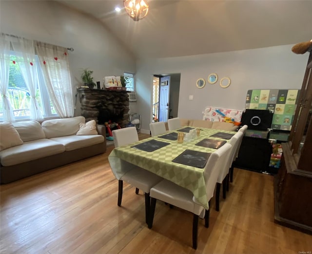 dining space featuring a fireplace, lofted ceiling, and light wood-type flooring