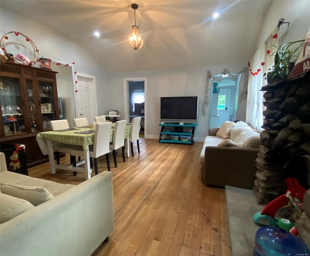 living room featuring lofted ceiling, hardwood / wood-style flooring, and a notable chandelier