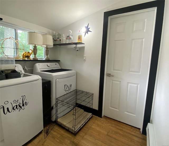 washroom with washing machine and dryer, baseboard heating, and hardwood / wood-style floors