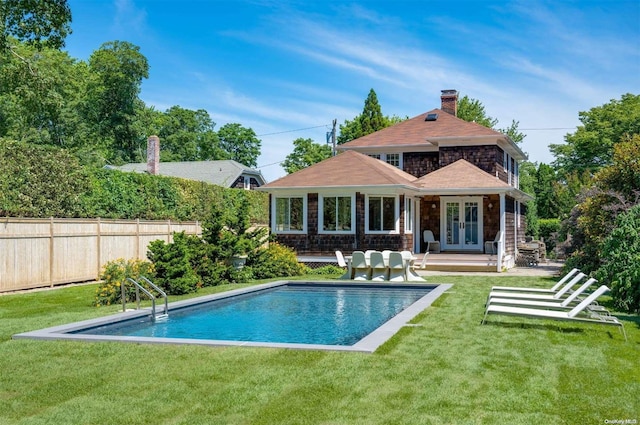 rear view of house featuring a fenced in pool, a patio area, french doors, and a lawn