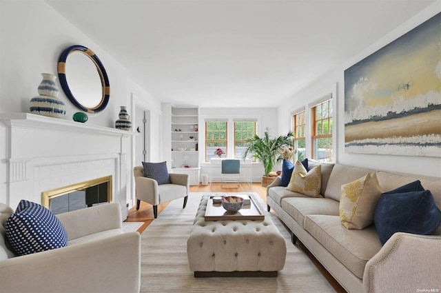 living room with built in shelves, a fireplace, and light hardwood / wood-style floors