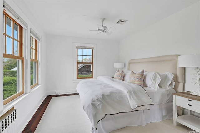 bedroom featuring hardwood / wood-style flooring, ceiling fan, and radiator heating unit