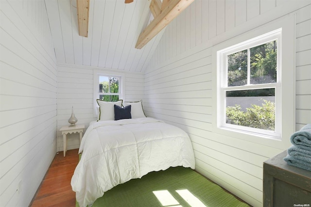 bedroom featuring lofted ceiling with beams, dark hardwood / wood-style floors, and wooden walls