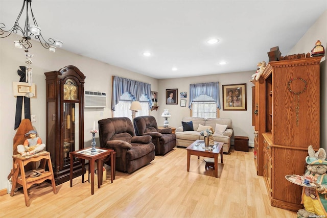 living room with light hardwood / wood-style floors, an AC wall unit, and an inviting chandelier