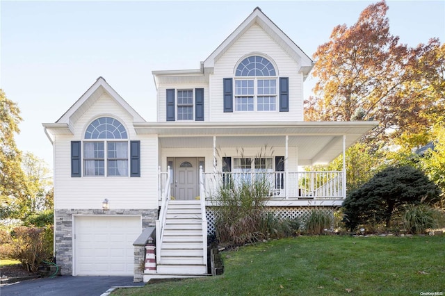 view of front of property featuring covered porch, a garage, and a front lawn