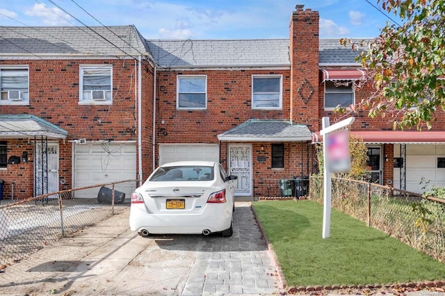 view of property with a garage, a front lawn, and cooling unit