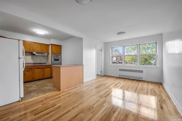 kitchen featuring radiator heating unit, white fridge, oven, and light hardwood / wood-style flooring