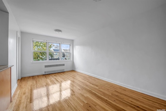 spare room featuring radiator heating unit and light wood-type flooring