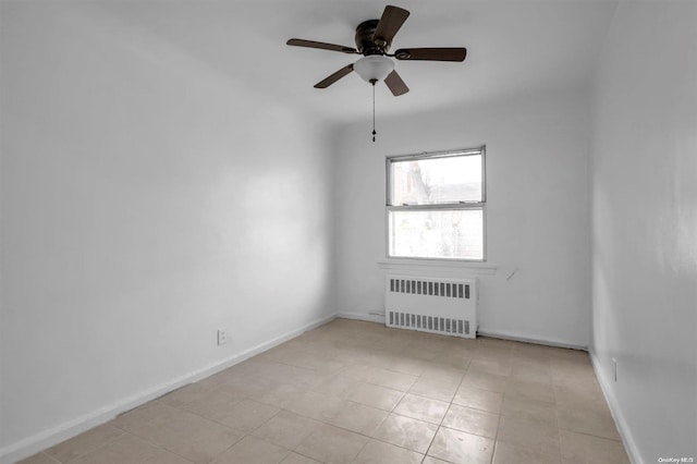 spare room featuring ceiling fan, light tile patterned flooring, and radiator heating unit