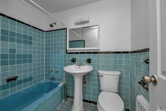 bathroom featuring tiled shower / bath combo, tile walls, tile patterned flooring, radiator heating unit, and toilet