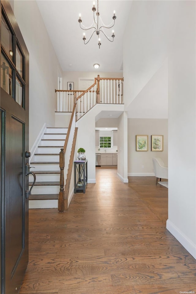 entryway featuring an inviting chandelier, high vaulted ceiling, and dark wood-type flooring