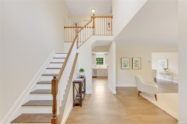 stairway with a towering ceiling and hardwood / wood-style flooring