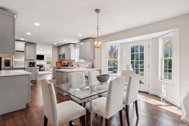 dining room with dark hardwood / wood-style flooring, an inviting chandelier, and sink